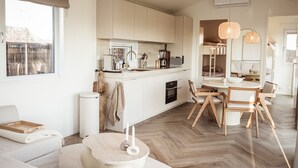 Una cocina moderna con armarios blancos, una isla central y una zona de comedor con sillas de madera y una mesa redonda.