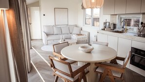 Una cocina moderna con armarios blancos, una mesa redonda para comer y sillas de madera.