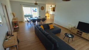 A modern living room with a sectional sofa, a dining area with a table and chairs, and a kitchen in the background. - Villa with 4 bedrooms and pool (FRESPECH)