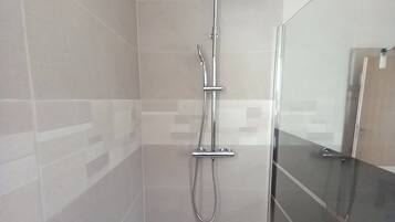A modern shower with a rain shower head, handheld showerhead, and a handheld hose.