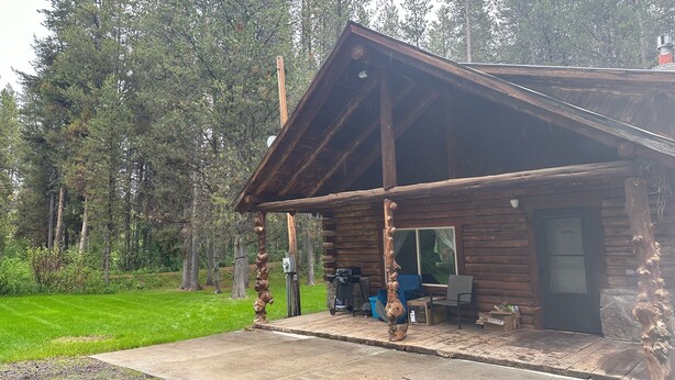 Una cabaña rústica con fachada de madera, un porche y una ventana.