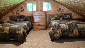 Un dormitorio acogedor en el ático con dos camas, un tocador y una ventana.