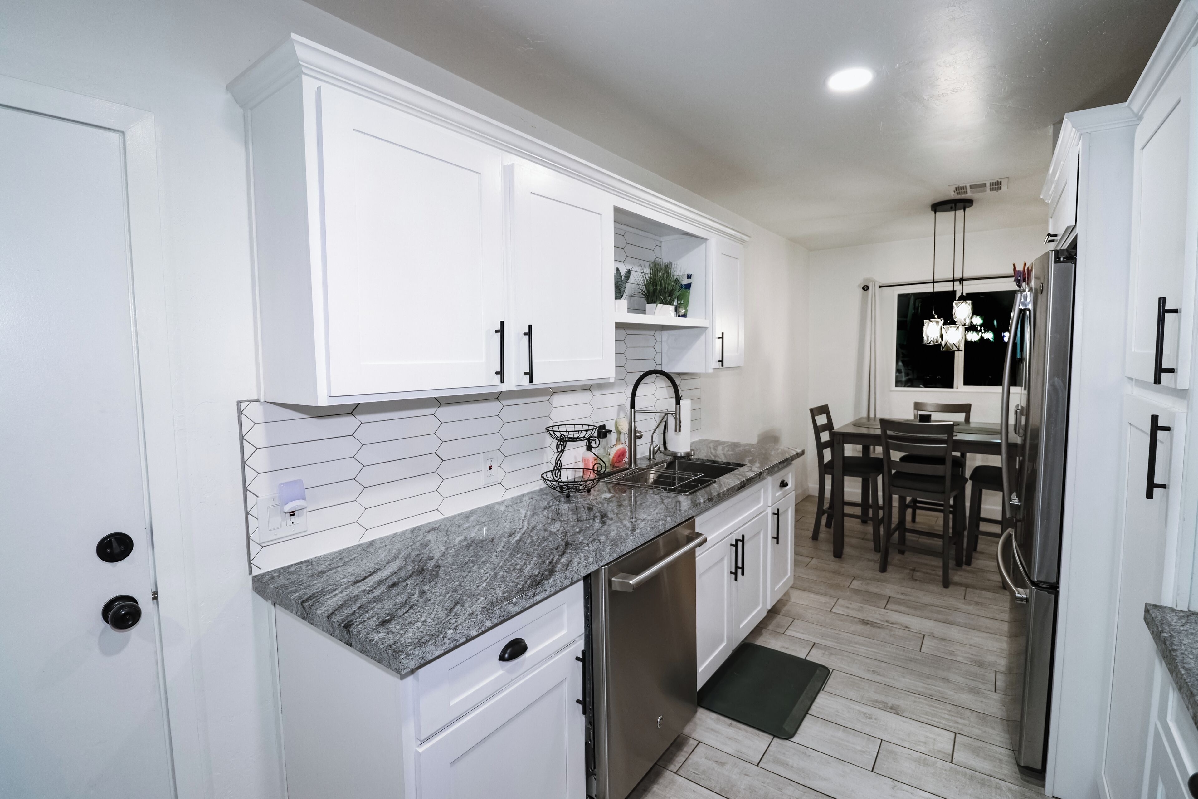 A modern kitchen with white cabinetry, a granite countertop, and stainless steel appliances.