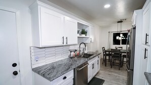 A modern kitchen with white cabinetry, a granite countertop, and stainless steel appliances. - Beautiful home with backyard oasis!  Great Location for Spring Training trips! (Phoenix)