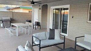 An outdoor patio area with a grill, seating, and a ceiling fan. - Beautiful home with backyard oasis!  Great Location for Spring Training trips! (Phoenix)