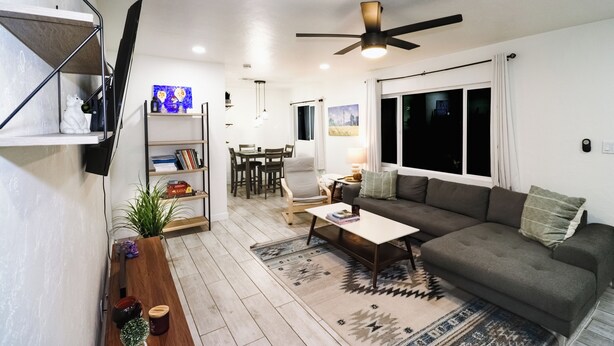 A modern living room with a sofa, coffee table, and a TV mounted on the wall. - Beautiful home with backyard oasis!  Great Location for Spring Training trips! (Phoenix)