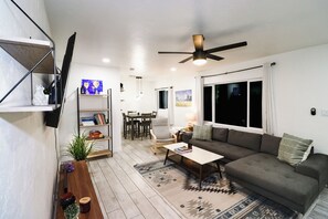 Un salon moderne avec un canapé, une table basse et un téléviseur fixé au mur.