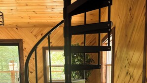 A spiral staircase in a wooden room with a view of the outdoors.