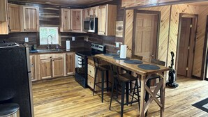 A wooden kitchen with a central island, stainless steel appliances, and a black refrigerator.