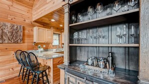 A rustic wooden interior with a bar area, wooden cabinets, and a seating area with chairs. - Mountain Views, Hot Tub, Pool Table, Fire Pit, Dogs Welcome, 3 King Beds (Sevierville)