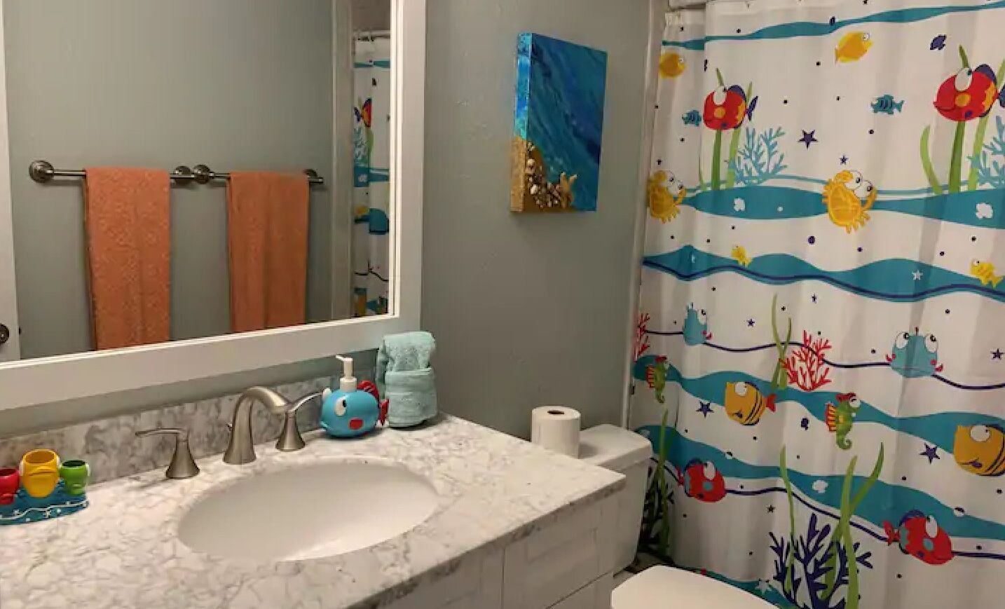 A bathroom with a white sink, a mirror, and a shower curtain with a marine theme.