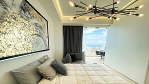 Una camera da letto moderna con un letto grande, vista sul balcone e un lampadario contemporaneo.