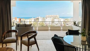 Un soggiorno moderno con un balcone, un tavolo rotondo in vetro e due sedie di legno.