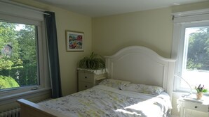 Et soveværelse med en seng, et natbord, et vindue og en radiator.