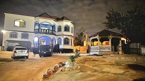 A large, multi-story house with a well-lit driveway and a small garden. - Beautiful Top Apartment in St. Elizabeth, Jamaica with an amazing Mountain View! (Junction)