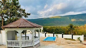 A gazebo with a tiled roof, a swimming pool, and a view of a mountainous landscape. - Beautiful Top Apartment in St. Elizabeth, Jamaica with an amazing Mountain View! (Junction)