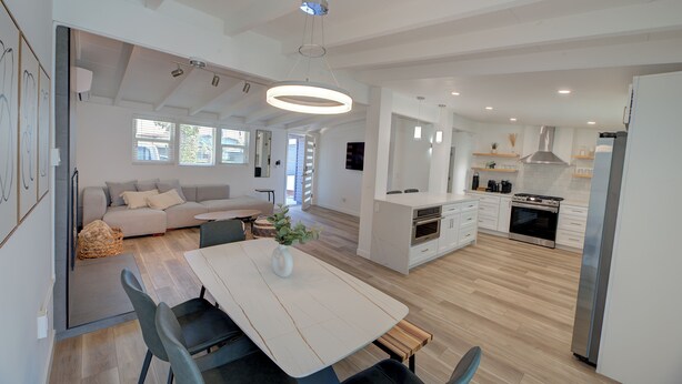 A modern kitchen with a central island, a dining area with a table and chairs, and a living space with a sofa and a coffee table.