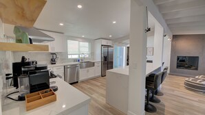 A modern kitchen with white cabinets, a built-in oven, and a coffee machine.