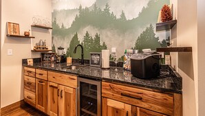 Eine Küche mit Holzausstattung, einer Arbeitsplatte aus Granit und einer Wandmalerei mit Bergmotiv.