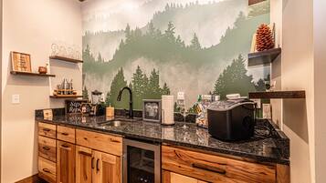 A kitchen with wooden cabinets, a granite countertop, and a mountain mural on the wall.