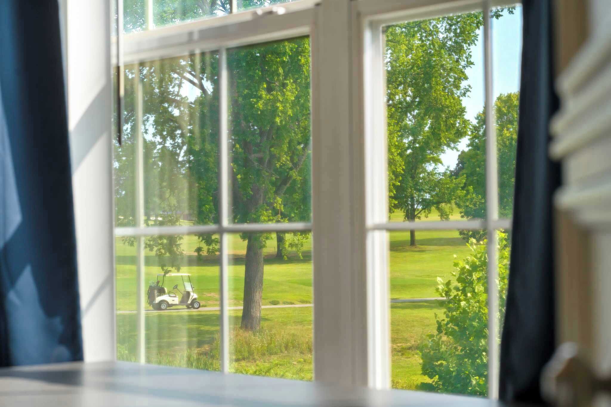 Een uitzicht op een golfbaan vanuit een raam.