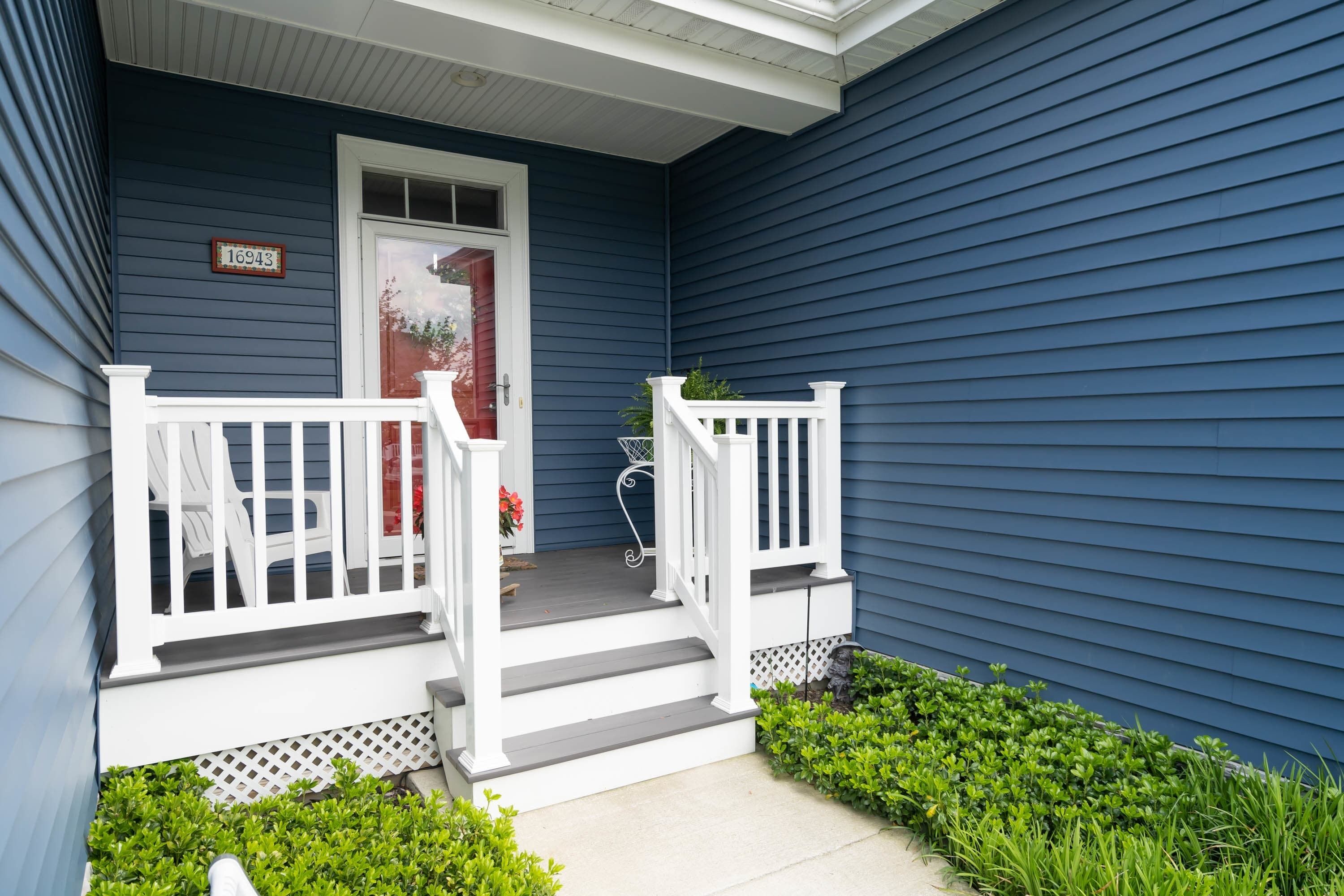 A house with a blue exterior, a white front porch with steps, and a mailbox.