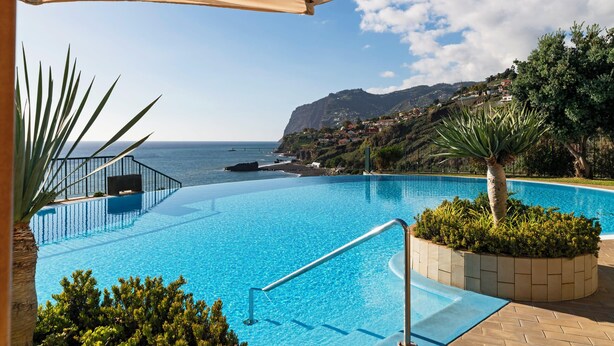 Une piscine offrant une vue sur l’océan et un paysage montagneux.