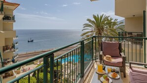 Un balcon avec une piscine, une table à manger et une vue sur la mer.