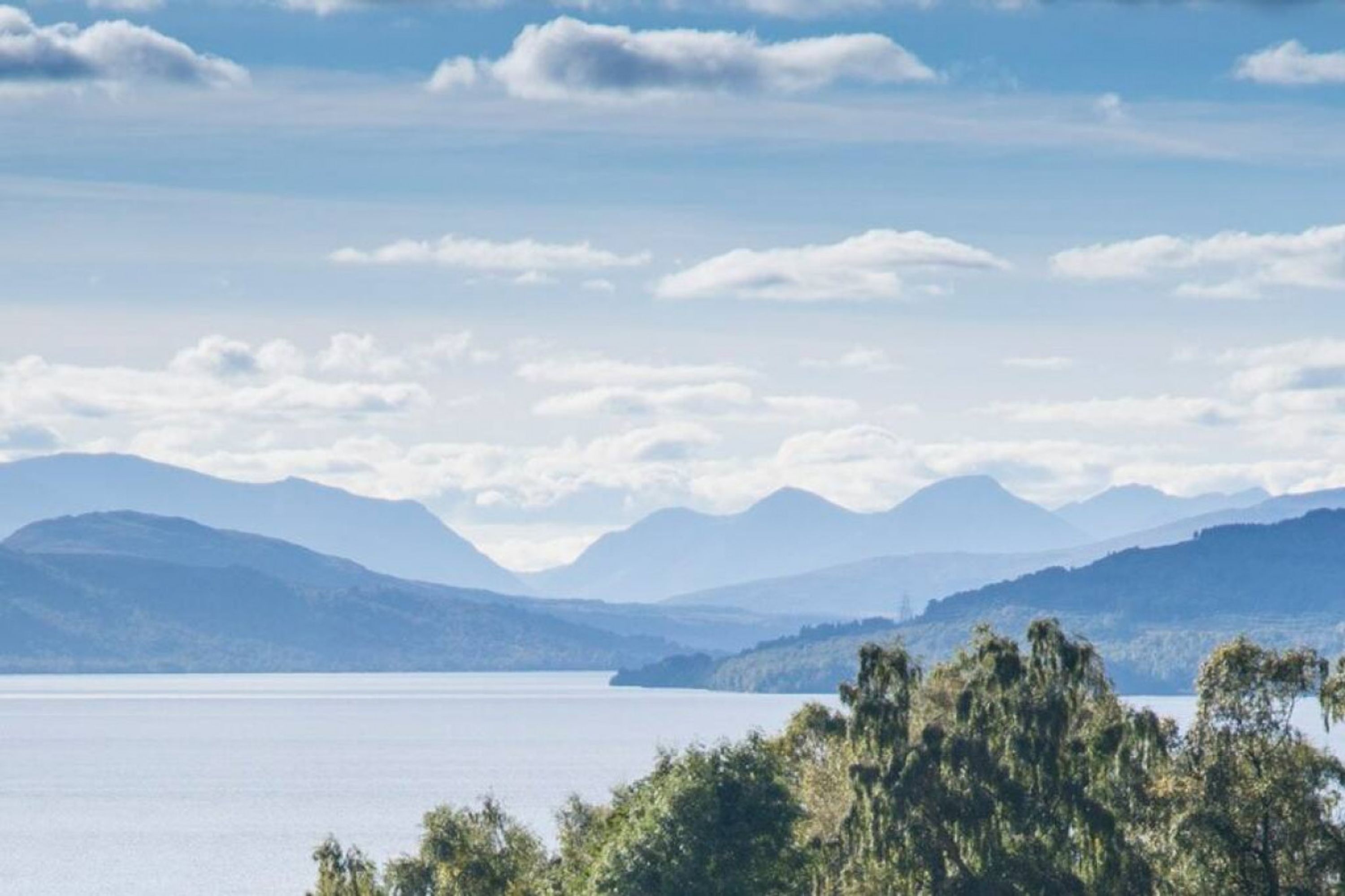 A lake with mountains in the background and trees in the foreground.