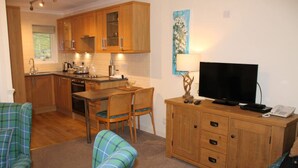 A compact living space with a kitchenette, dining area, and seating area. - Lochside Lodge 07 Loch Rannoch Highland Club (Pitlochry)