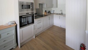 Una cucina compatta con mobili bianchi, un forno a microonde, un forno e un lavello.