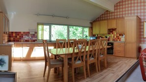 Une cuisine avec des meubles de rangement en bois, une table à manger avec des chaises et une fenêtre qui laisse entrer la lumière naturelle.