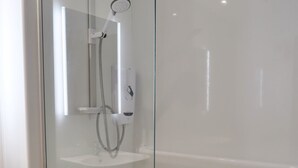 Eine Duschkabine mit Glaswänden, einer Handbrause, einer Bedienkonsole und einem kleinen Ablagebrett.