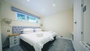 A bedroom with a bed, bedside tables, a window, and a radiator. - Apartment 09 Loch Rannoch Highland Club (Pitlochry)