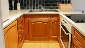 A kitchen with wooden cabinets, a white countertop, a sink, and a tiled backsplash. - Studio 06 Loch Rannoch Highland Club (Pitlochry)