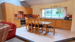 Eine kleine Küche mit Holzausstattung, einem Esstisch mit Stühlen und einem roten Sofa.
