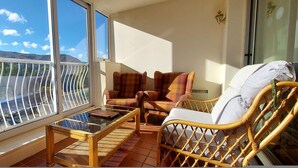 A balcony with a view of mountains, wicker furniture, and a glass table. - Studio 05 Loch Rannoch Highland Club (Pitlochry)
