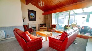 A living room with red leather sofas, a wooden coffee table, and a fireplace. - Highland Lodge 35 Loch Rannoch Highland Club (Pitlochry)