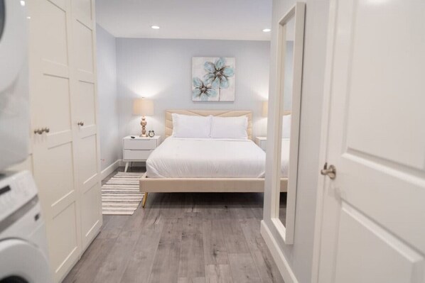 Una camera da letto con un letto, comodini, una lampada e un quadro appeso al muro.