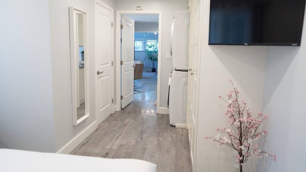 A hallway with white doors, a mounted flat-screen TV, and a wooden floor. - 1BR House in Glendale With Private Fenced Yard p55 (Glendale)
