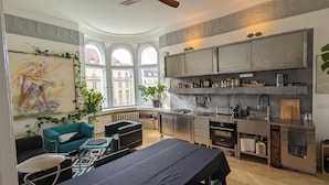 Eine moderne Küche mit integriertem Herd, Backofen und Mikrowelle. Es gibt einen Essbereich mit Tisch und Stühlen, sowie ein großes Fenster, das für natürliches Licht sorgt.