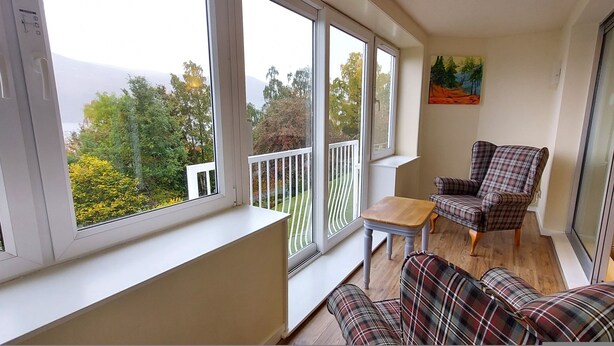 A room with a balcony, plaid furniture, and a painting on the wall.