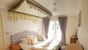 A bedroom with a tufted headboard, a wooden nightstand, a wooden bench, and a bed with floral bedding. - Highland Lodge 06 Loch Rannoch Highland Club (Pitlochry)