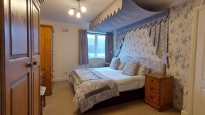 A bedroom with a bed, a wooden dresser, a window with curtains, and a door. - Highland Lodge 40 Loch Rannoch Highland Club (Pitlochry)