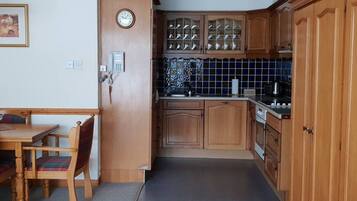 Una cocina compacta con armarios de madera, horno integrado y salpicadero de azulejos.