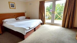 A bedroom with a wooden bed, two bedside tables, a nightstand, and a window with curtains. - Red Squirrel Lodge 03 Loch Rannoch Highland Club (Pitlochry)