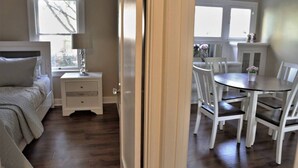 Ein Schlafzimmer mit Bett, Nachttisch und Kommode. Es gibt eine Essecke mit Tisch und Stühlen.