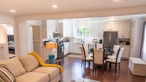 A modern kitchen with white cabinets, a dining area with a glass table, and a living room with a beige sofa. - Tranquil 2BR Home in Beautiful Neighborhood P24 (Burbank)