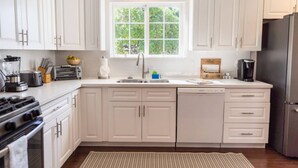 A modern kitchen with white cabinets, a large window, and a stainless steel refrigerator. - Tranquil 2BR Home in Beautiful Neighborhood P24 (Burbank)