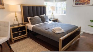 A modern bedroom with a large bed, two bedside tables, a chair, and a window with blinds. - Tranquil 2BR Home in Beautiful Neighborhood P24 (Burbank)